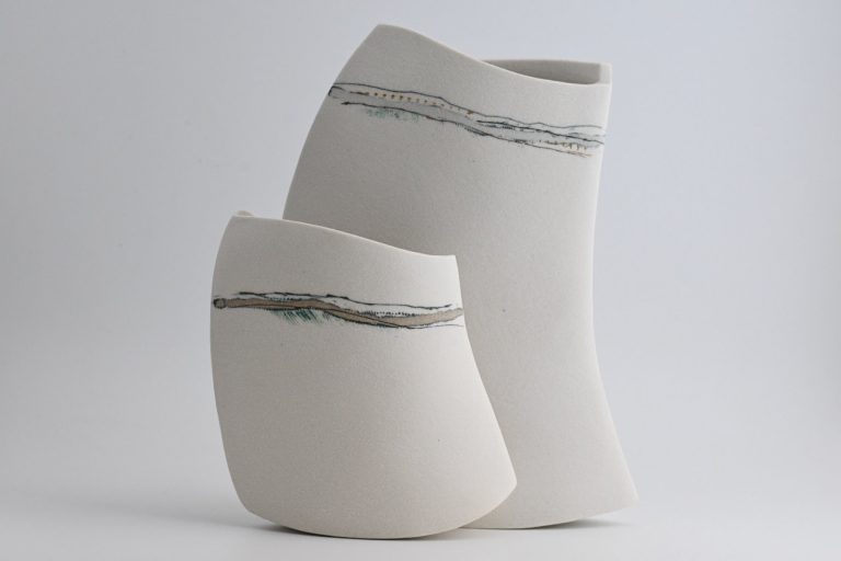 Deux pots en céramique blanche à liseré gris moyen de forme courbée.